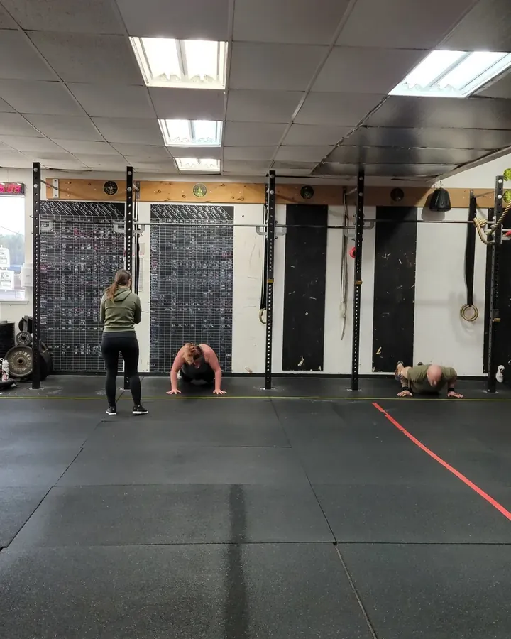 The CrossFit Deluge training floor, with members training in front of the rig and climbing ropes.